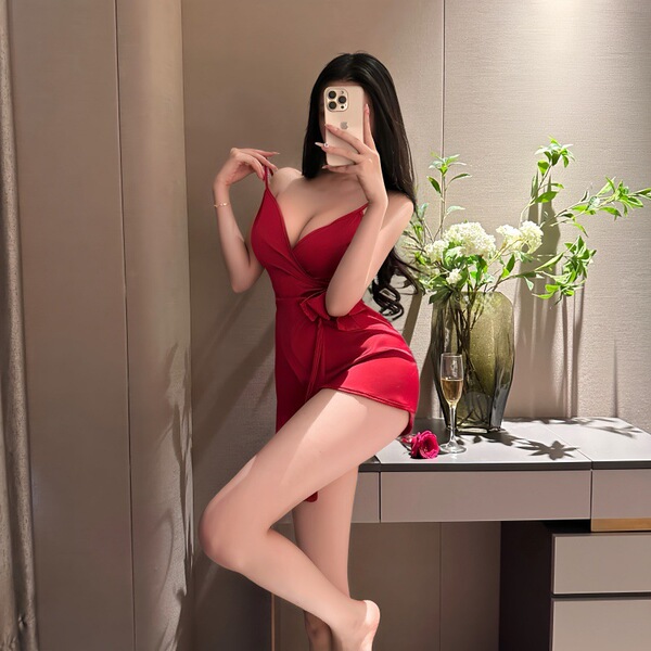 Woman in red pure & alluring lace-back sleepwear set, posing with phone, ice silk pajamas with adjustable ties.