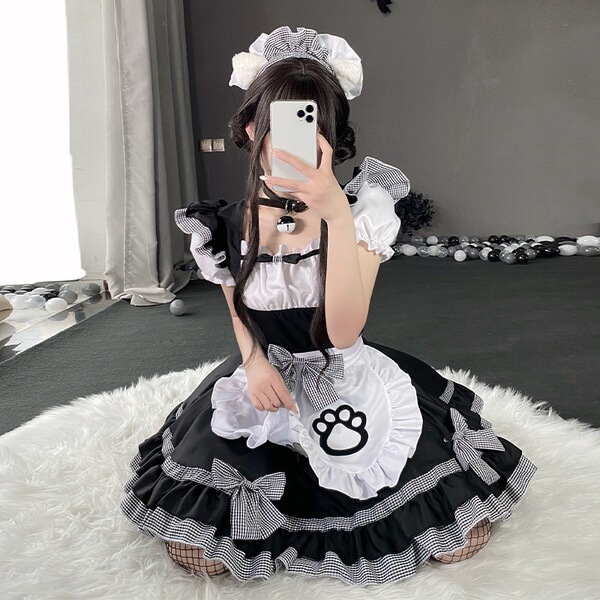 A person wearing a black and white maid costume with a cat paw design, sitting on a fluffy rug while taking a selfie.