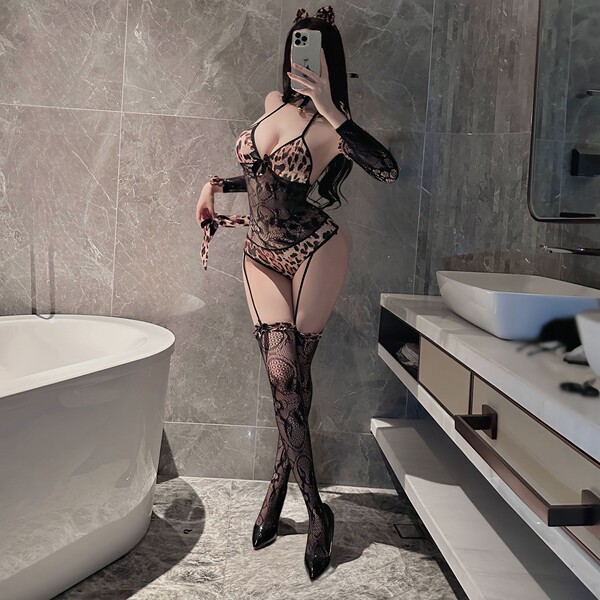 Woman in bathroom wearing sexy leopard print catwoman bodysuit with lace sleeves, garter belt, and thigh-high stockings for r...