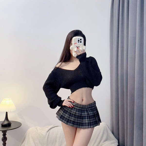 A woman poses with a phone featuring a cute bear case, wearing a black sheer sweater and a plaid micro skirt, showcasing a pl...
