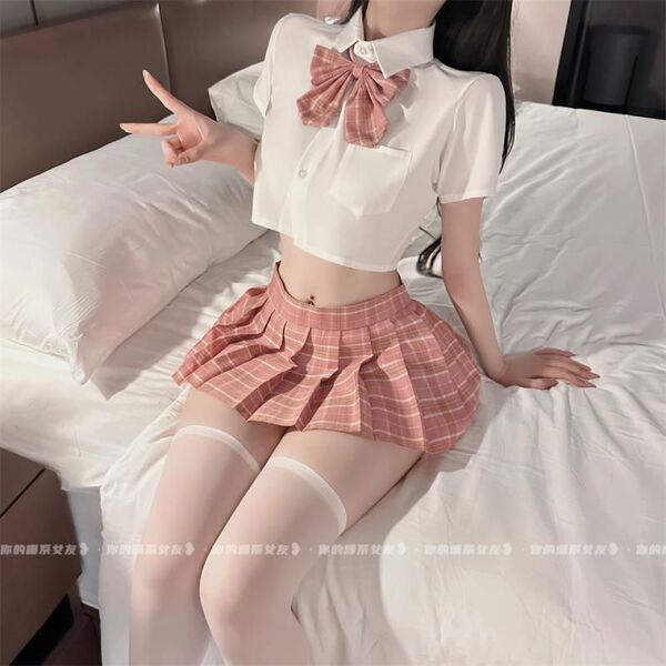 Woman wearing plus size sexy jk uniform set with white crop top, pink plaid bow tie, pleated mini skirt, and thigh-high stock...