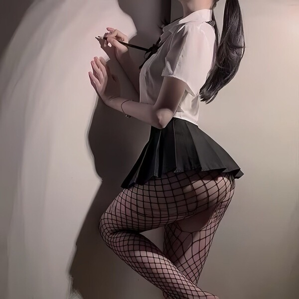 Woman wearing a sexy jk uniform set with a white crop top, black pleated skirt, and fishnet stockings.