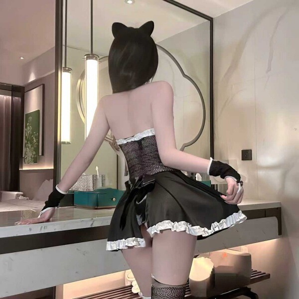 Woman wearing black cat ears and a sheer off-shoulder maid-style lingerie set, posing in a modern bathroom.