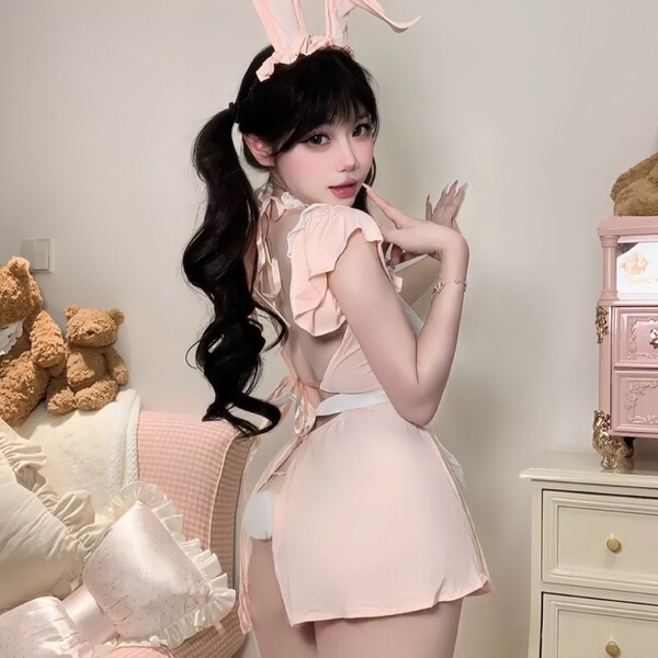 Woman modeling pink lace bunny girl costume with ruffled trim and sheer mesh details, perfect for cosplay or themed events.