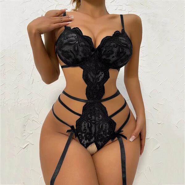 Woman wearing black luxury lace sheer bodysuit with floral detailing and strappy design.