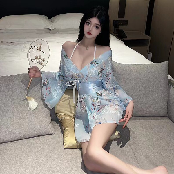 A woman lounges on a couch wearing a japanese-style sexy lace kimono robe set. the sheer chiffon dress features floral embroi...