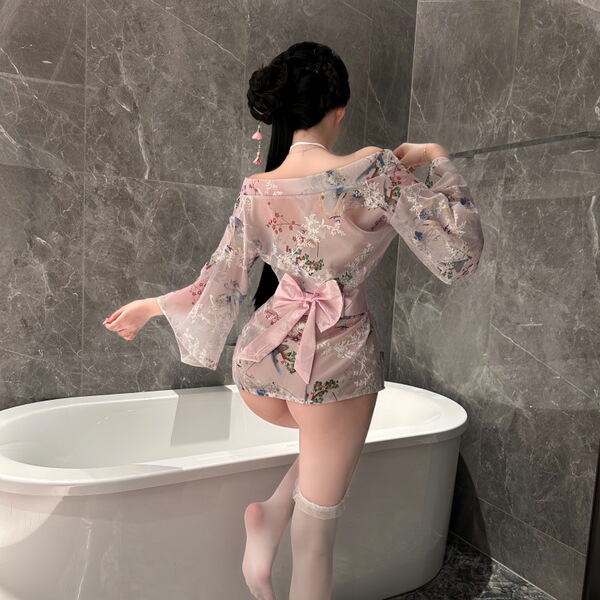 Woman wearing pink floral nightsiyese lingerie set with bow, standing by bathtub in japanese-inspired costume.