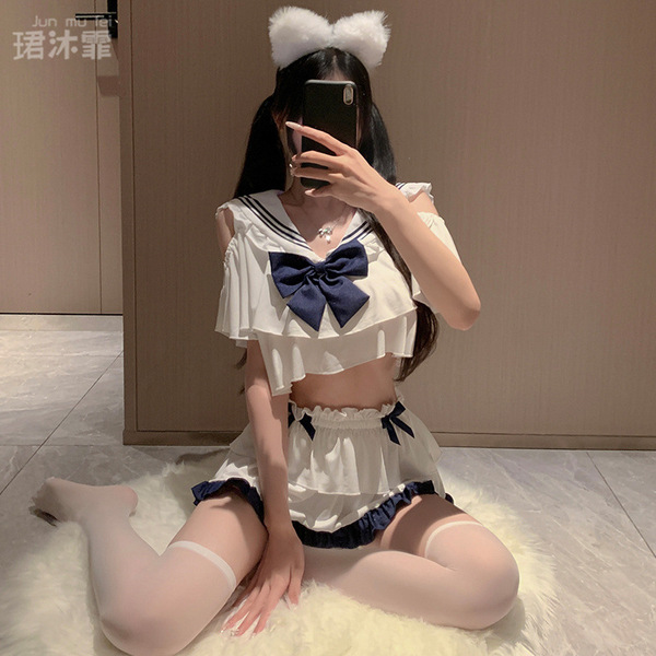 A person wearing a cute jk student uniform outfit, featuring a sailor-style top with ruffles and a large bow, paired with mat...
