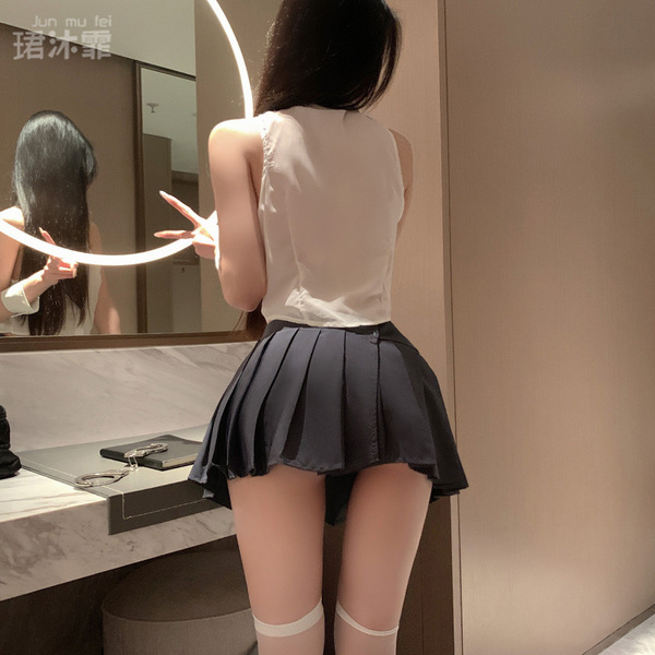 A woman stands facing a mirror wearing a white blouse paired with a pleated black skirt, creating a cute schoolgirl outfit. t...