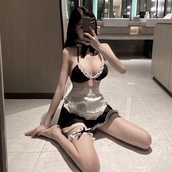 Woman posing in mirror wearing sexy maid-style lingerie sleep dress with open-crotch design, lace trim, and thigh-high stocki...
