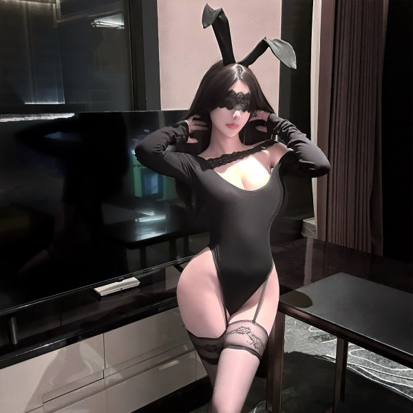 Woman wearing black chaomu temptation lingerie bodysuit with bunny ears, lace mask, and thigh-high stockings in modern room.
