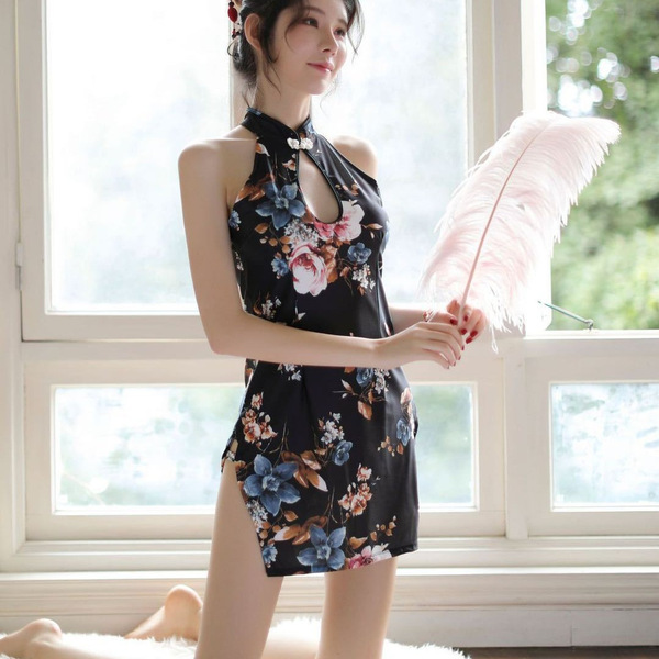 A woman stands by a window wearing a floral halter bodysuit, holding a feather fan. the dress features a retro design with mo...