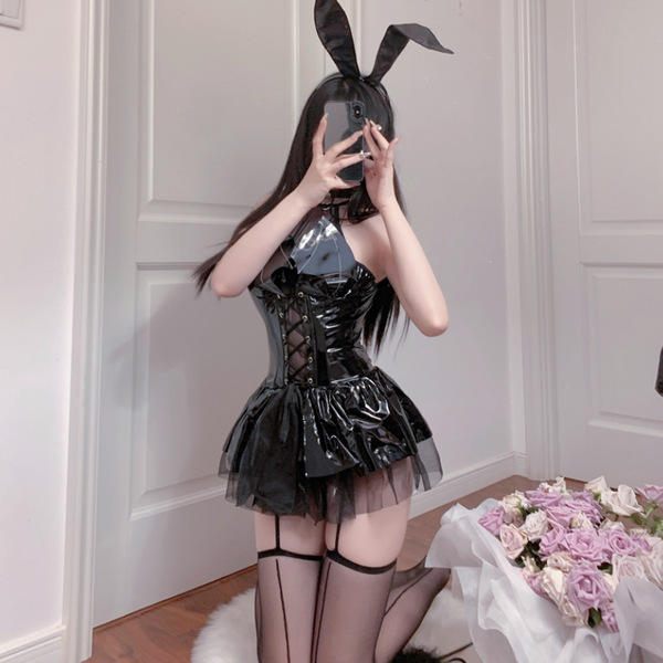 A person wearing a shiny black gueiyun pu lace devil wing set, featuring a mini dress with halter tie straps and bunny ears, ...