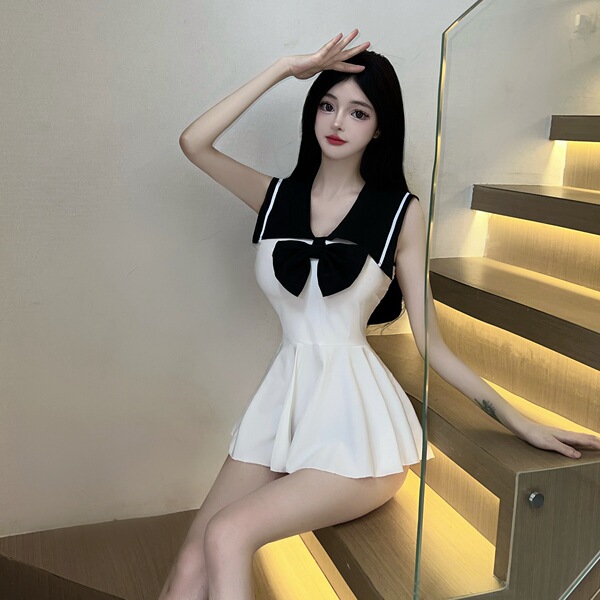 Woman wearing white and black sailor-style jk uniform set, posing on stairs with hand on head.