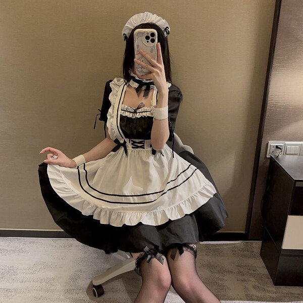 A person wearing a japanese maid costume dress, featuring black and white colors with ruffles and bows, suitable for cosplay ...