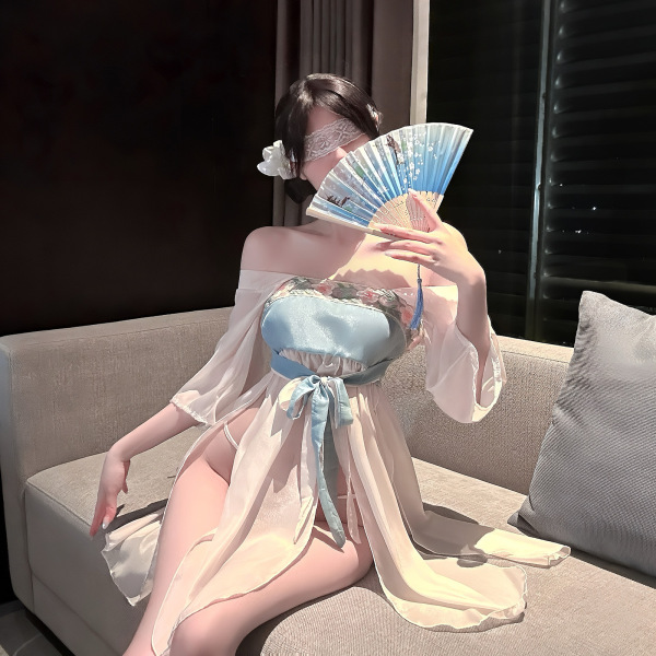Woman wearing jinxiao lingerie set, elegant chinese-inspired silk babydoll and robe with fan, posing on sofa.