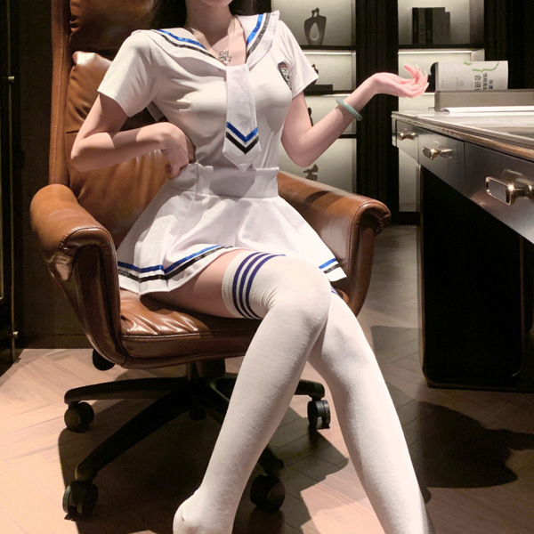 A woman sits confidently in an office chair wearing a white sailor-style jk uniform set, featuring blue accents and thigh-hig...