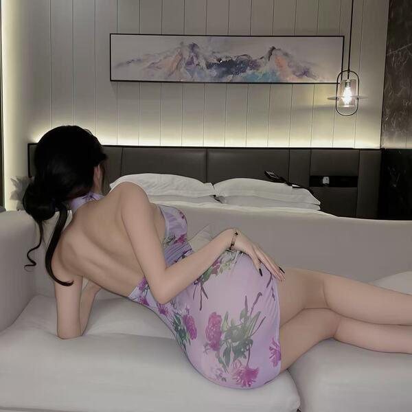 A woman lounges on a couch wearing a floral nightwear set, featuring a sheer silk blend robe and modest panty, inspired by cl...