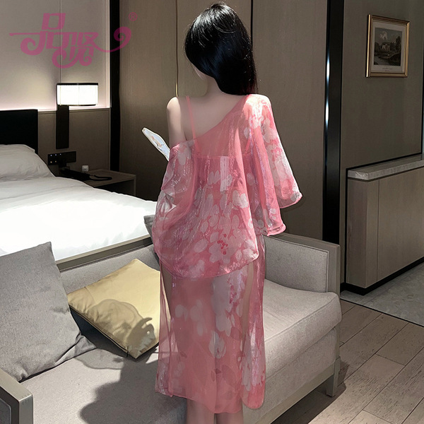 A woman stands facing away from the camera, wearing a delicate pink cherry blossom design sleepwear set by pinxian. the sheer...