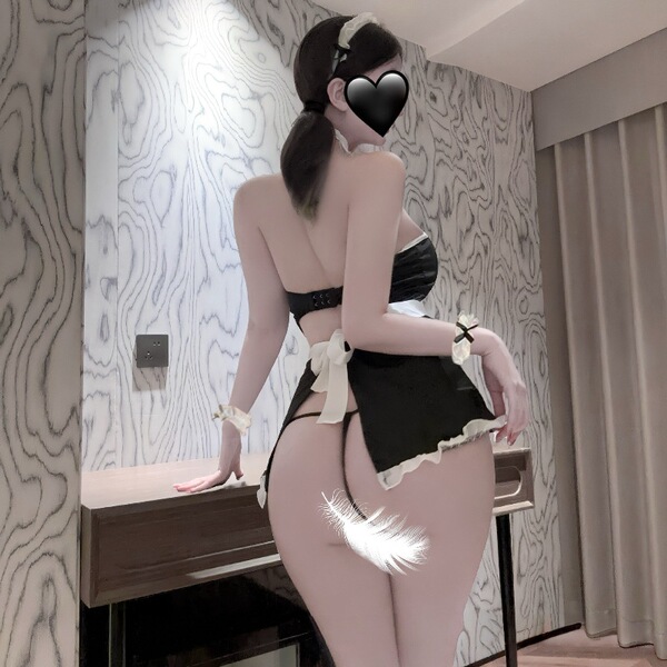 Woman modeling black plus size maid costume lingerie set with open-crotch design, white bows, and feather detail for adult ro...