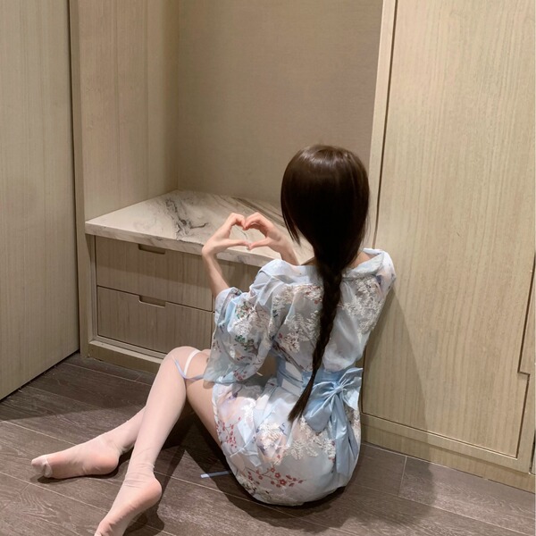 A woman sits on the floor wearing a delicate, floral-patterned kimono sleepwear set. the soft fabric features intricate desig...