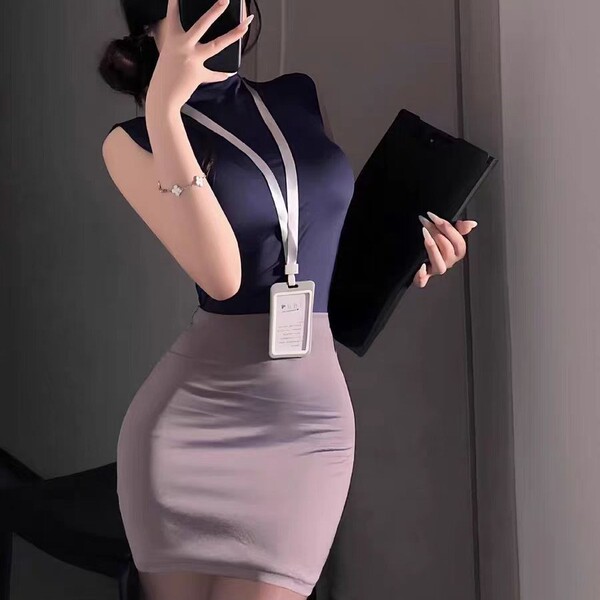 Woman in navy top and lavender skirt set, holding folder and phone, wearing id badge, styled as airline stewardess costume.