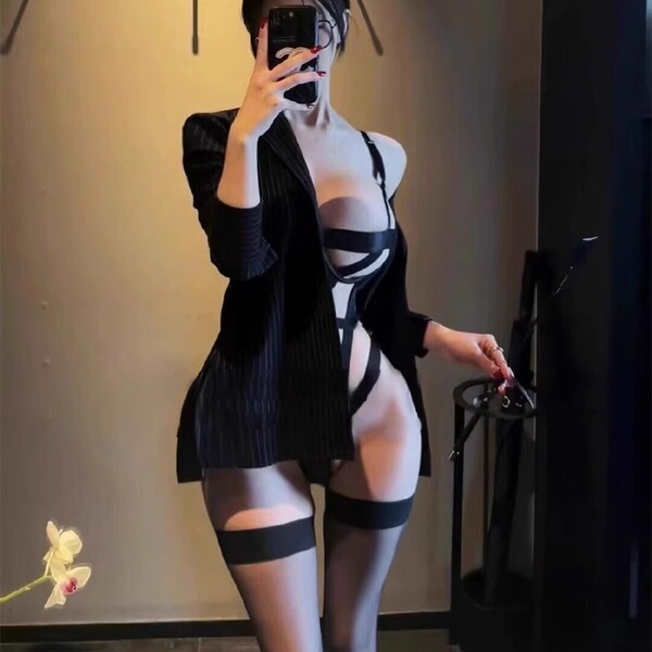 Woman modeling a sexy cross-back secretary costume with lace-up bodysuit, black blazer, and thigh-high stockings for role pla...