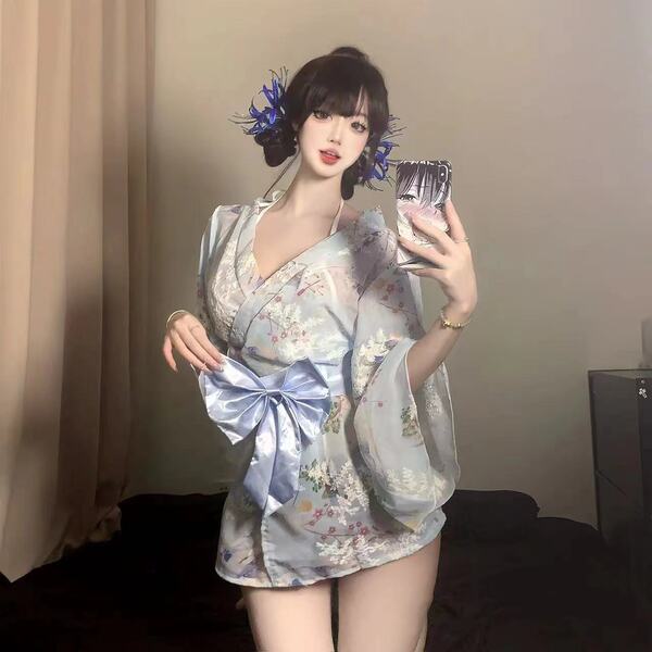 A woman poses with a smartphone, wearing a floral-patterned yukata robe. the light blue satin fabric features a large bow det...