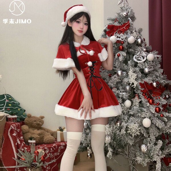 A festive woman poses beside a decorated christmas tree wearing a vibrant red velvet santa outfit, complete with a santa hat ...