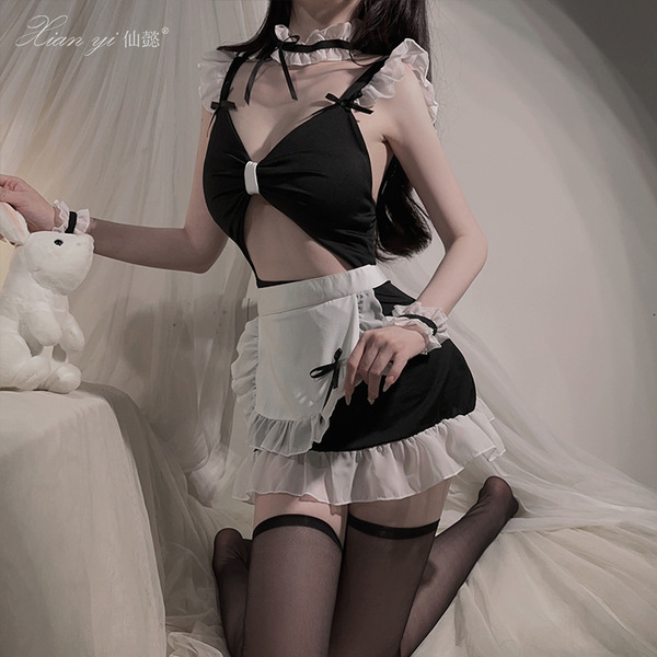 A woman poses in a black and white maid costume, featuring ruffled details and stockings, creating an elegant yet playful sce...