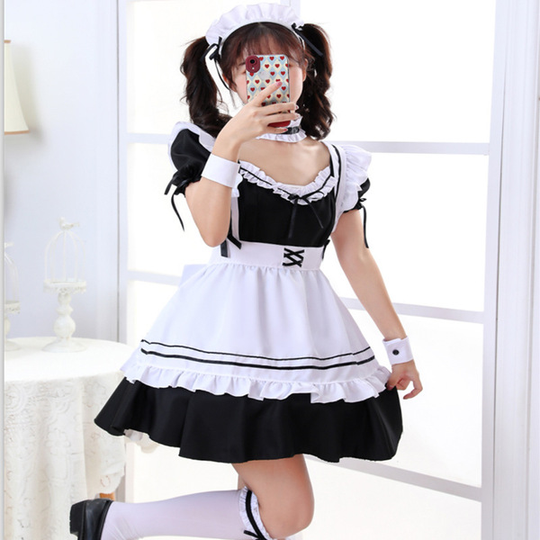 A girl wearing a black and white maid outfit with ruffles, posing indoors while taking a mirror selfie. the costume features ...