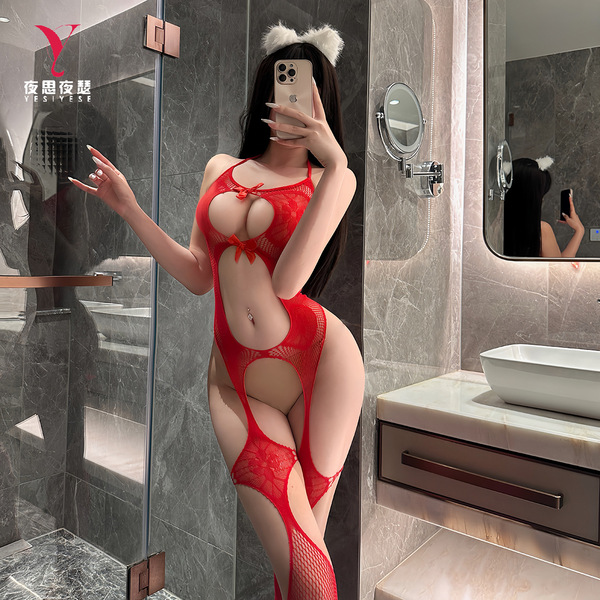 Woman in red nightsigh lace bodysuit with sheer mesh, halter neck, and cutouts, posing in a modern bathroom.