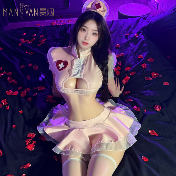 Woman in pink pure temptation nurse costume with lace lingerie, petticoat skirt, and nurse hat on bed with rose petals.