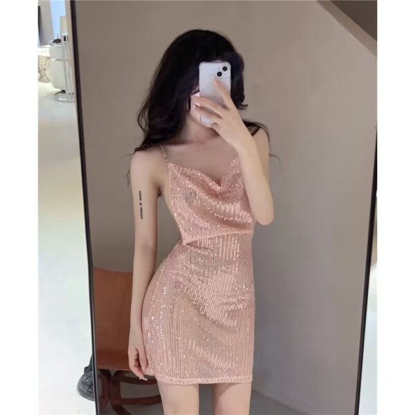 Woman in mirror wearing a sexy shiny pink sequin sleep dress with sheer backless design for nightclub or lingerie.
