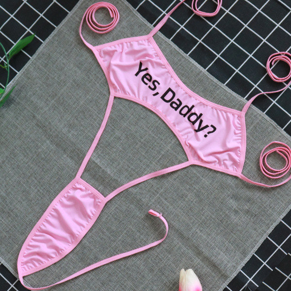 Pink yes, daddy? lingerie set on gray cloth with coiled straps, playful yet modest design for women.