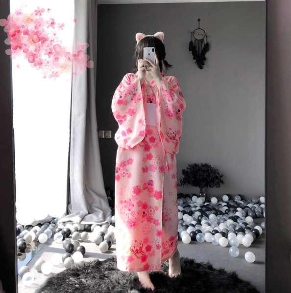 A person wearing a pink floral japanese-style kimono, complete with cat ears, takes a mirror selfie. the outfit features long...