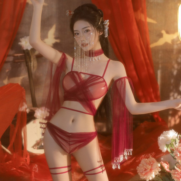 Woman wearing manny qing red sheer lace bralette set with hanfu-inspired details, posing in a warm, floral-lit setting.
