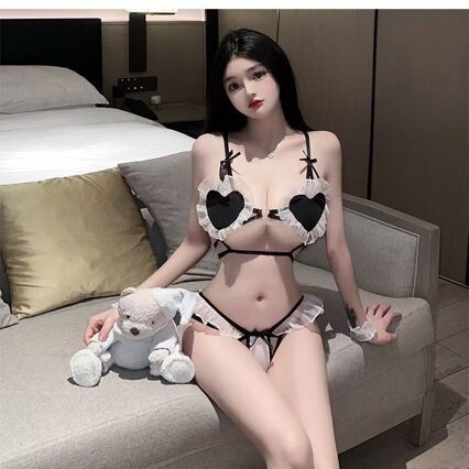 Woman in sexy maid costume with heart-shaped lingerie, sitting on couch with teddy bear. cute & seductive three-piece role pl...