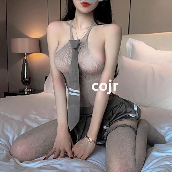 Woman in sexy student jk uniform set with lace bodysuit, tie, and sheer stockings on bed.