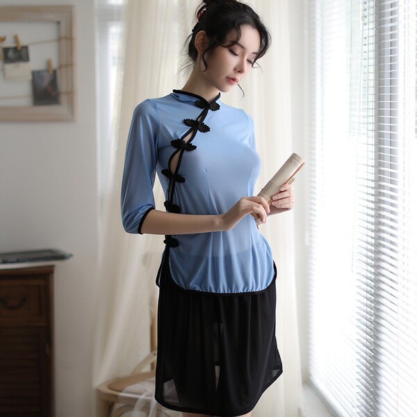 Woman in vintage chinese-inspired sheer lingerie set with side slit, holding a book by a window.