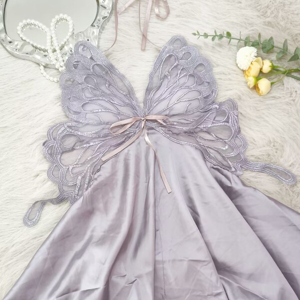 Lavender ice silk sleep dress with bow detail and backless cutout, styled on fluffy white rug with pearls and flowers.