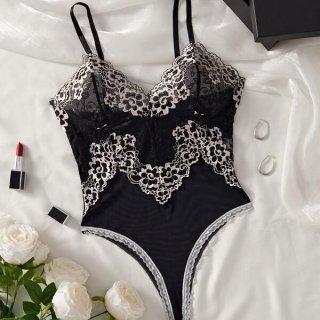 Black lace mesh bodysuit with floral details, styled as sensual sleepwear lingerie for women, displayed on white silk with ro...