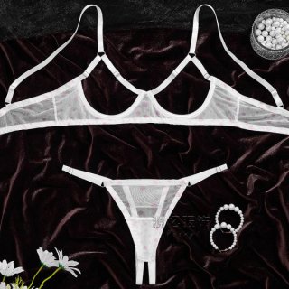 Sheer white bra and panty set with pink polka dots on dark velvet, styled with pearls and flowers.