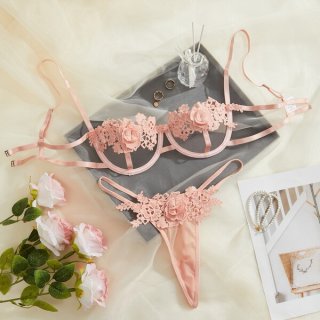 Pink lace lingerie set with floral details, displayed on a soft background with roses and accessories.