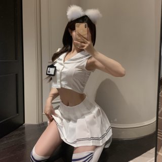 Woman in white sailor-style lingerie set with pleated skirt, crop top, and fluffy ears, posing playfully for mirror selfie.