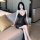 A woman sits on a couch wearing a black sheer mesh nightgown with a deep v-neckline, perfect for women seeking comfort and el...