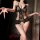 Woman modeling black nightsigh lace bodysuit with floral sheer fabric, open-crotch design and bow accents.