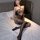 Woman modeling black lace mesh bodysuit with fishnet stockings on bed.