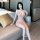A woman elegantly poses on a couch wearing a sheer, long nightgown with a deep v-neckline, perfect for a luxurious sleep expe...