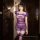 Woman wearing sexy purple lace bodycon nightgown with sheer fabric, ruffled sleeves, and matching thigh-high stockings in dim...